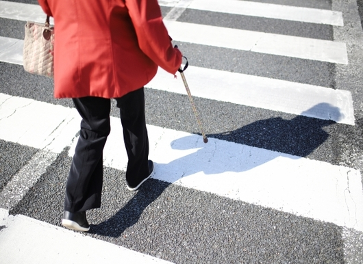 杖をついて横断歩道を歩く女性