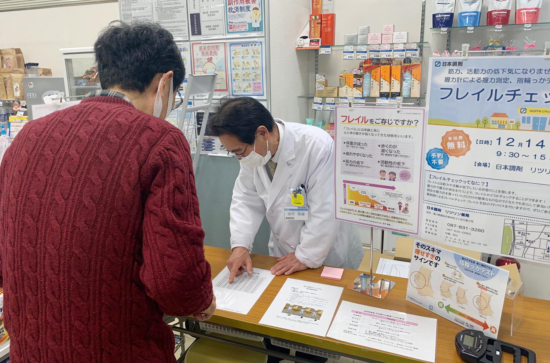 カウンター越しにフレイルについて説明する薬剤師
