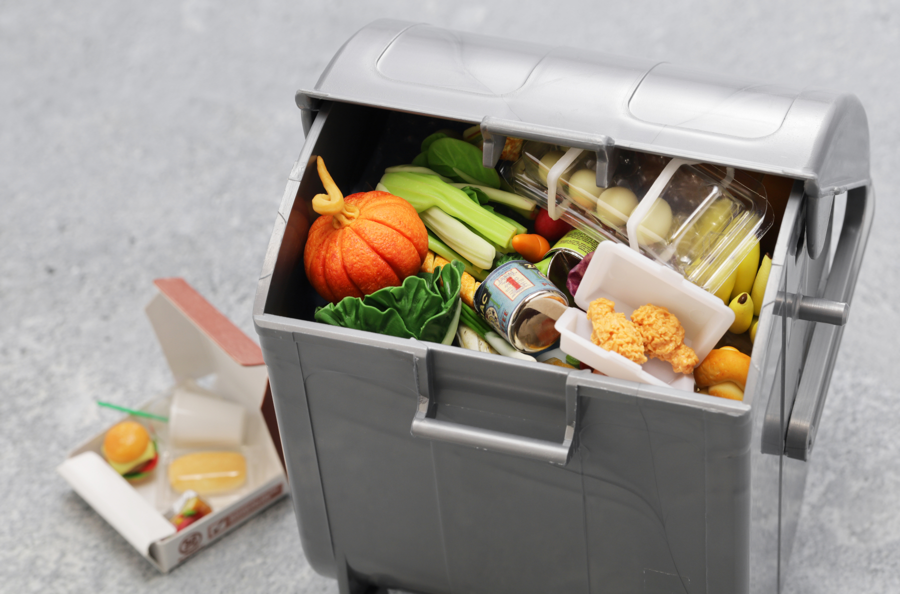 大量の食品がごみ箱に捨てられているミニチュア模型