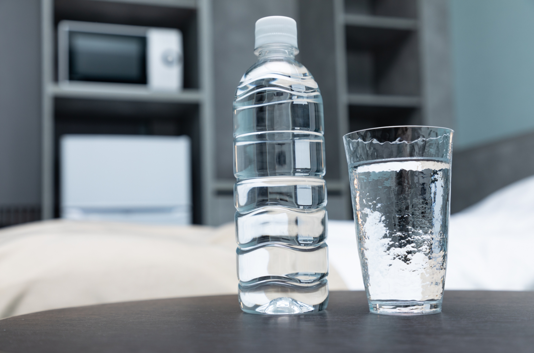 テーブルの上に置かれている水の入ったペットボトルとコップ