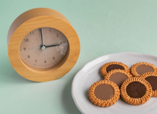 お皿に載ったクッキーと15時を示す置時計