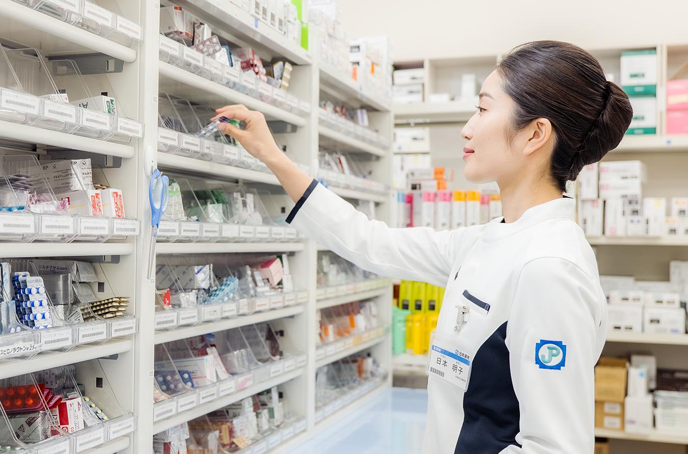 調剤棚に手を伸ばす女性薬剤師